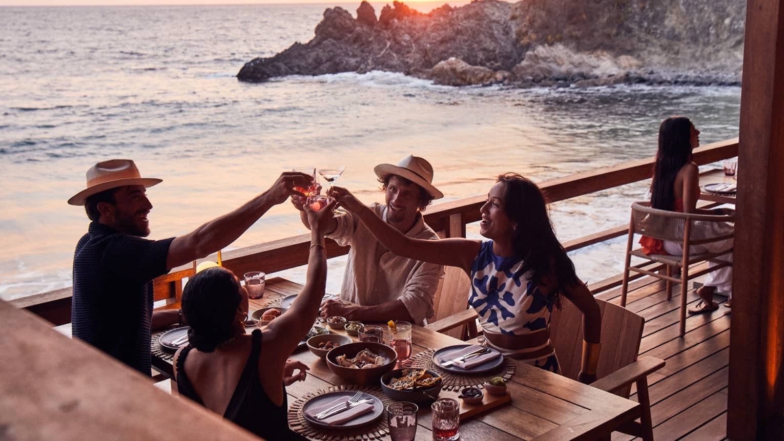 Friends raising a toast at a seaside restaurant at sunset